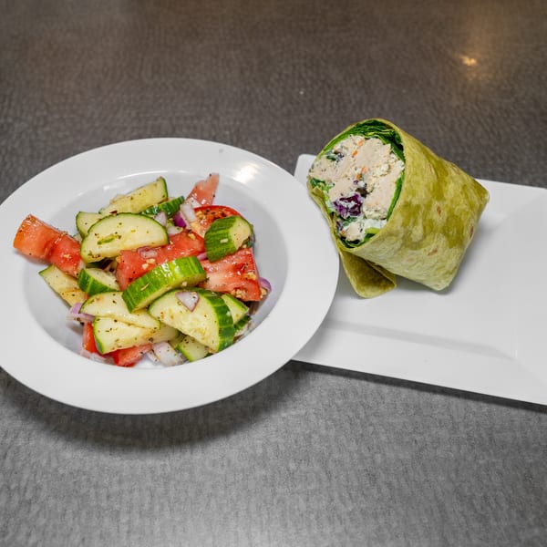 Chicken salad wrap with a side of cucumber, tomato, and red onion salad.