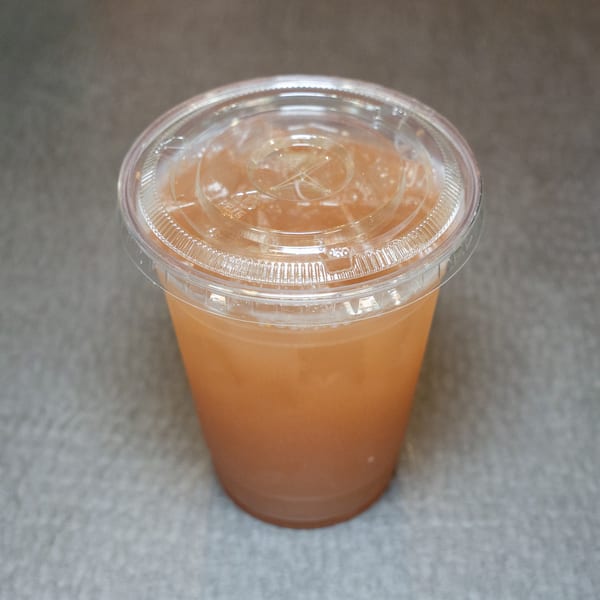 A clear plastic cup filled with a light brown beverage and a clear lid.