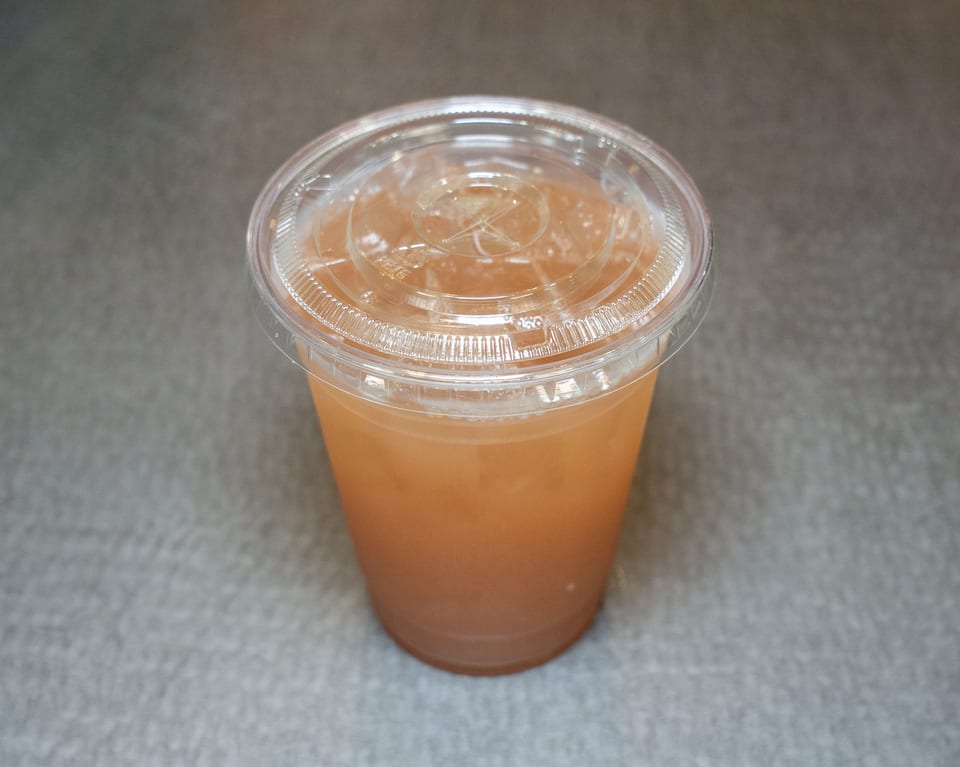 A clear plastic cup filled with a light brown beverage and a clear lid.
