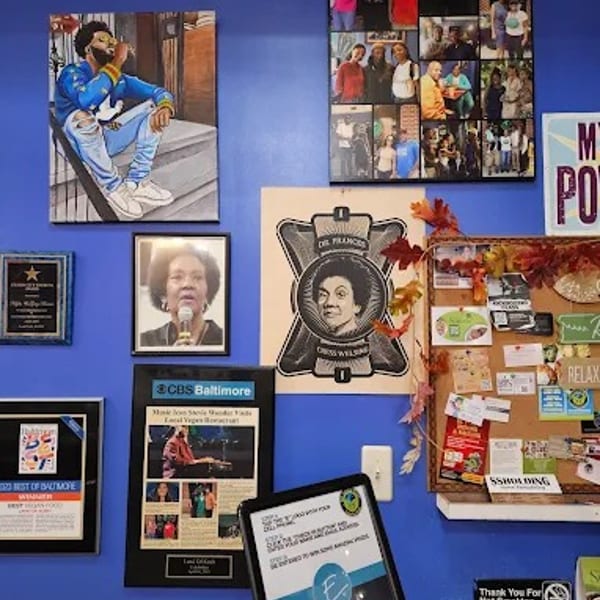 A vibrant blue wall adorned with framed artwork, awards, and a community bulletin board.