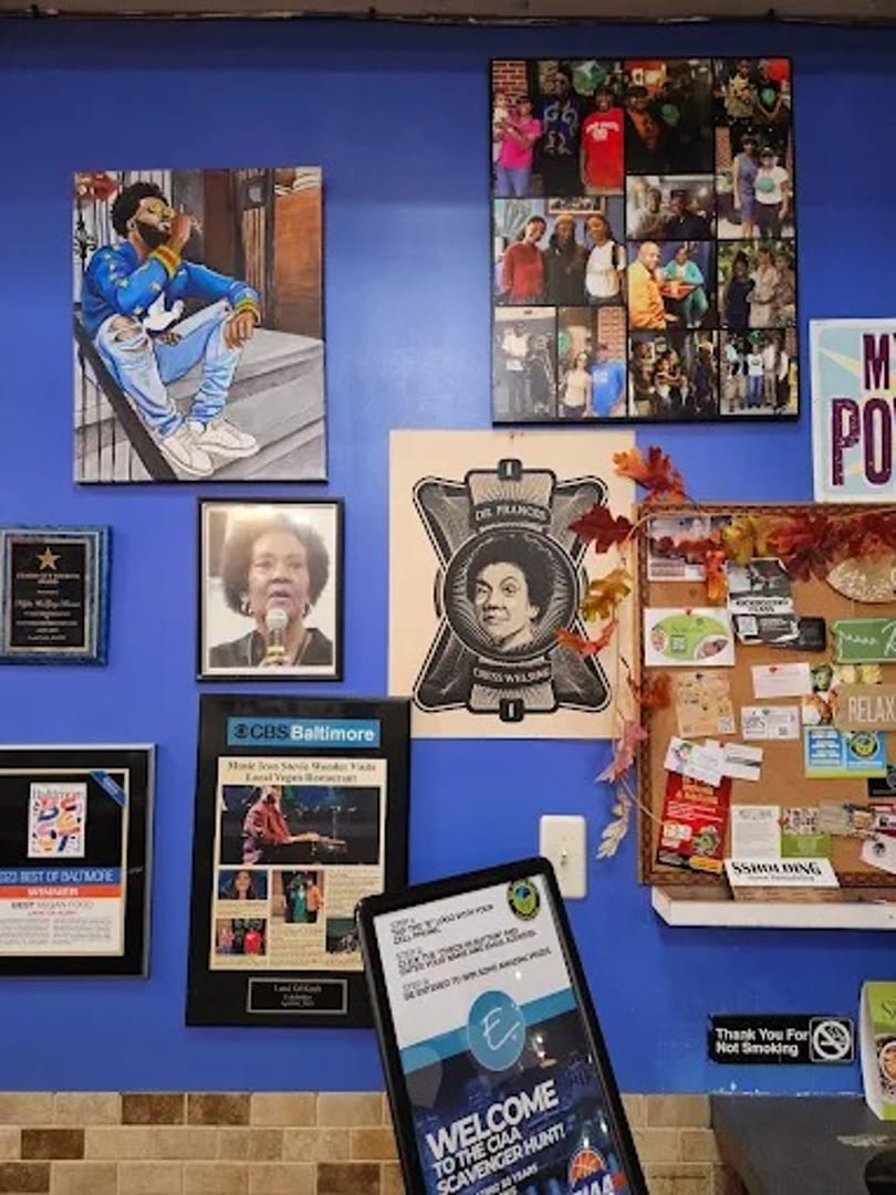 A vibrant blue wall adorned with framed artwork, awards, and a community bulletin board.